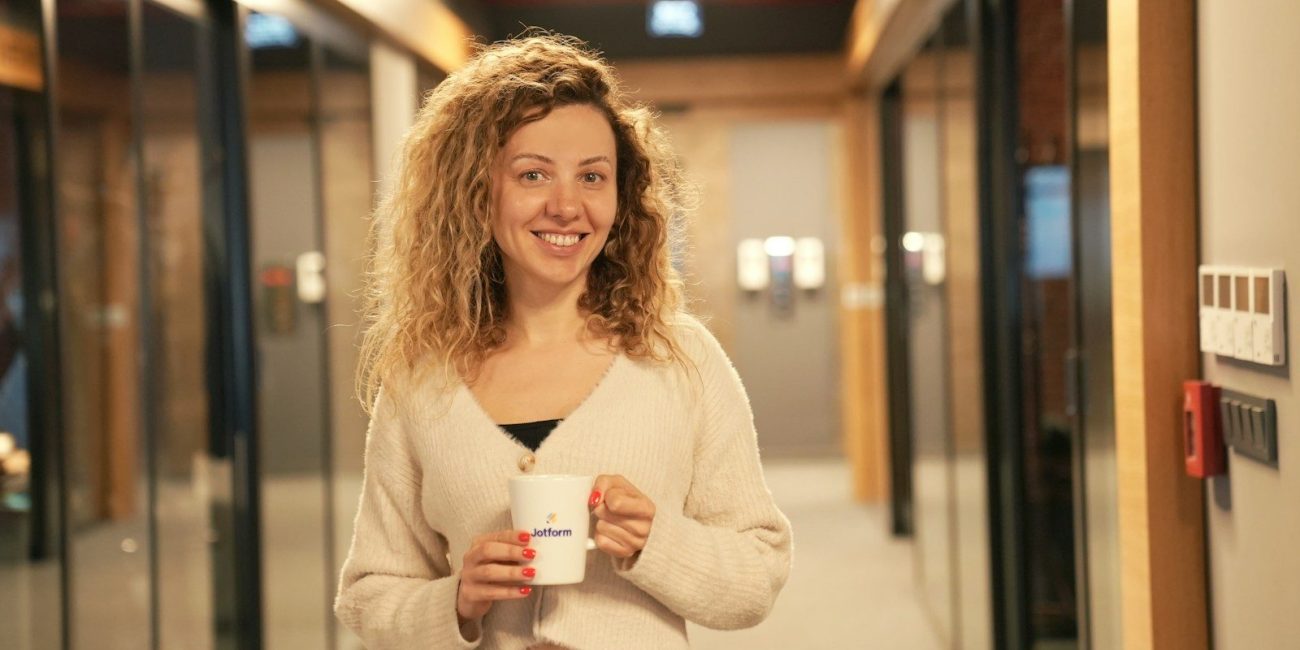a woman holding a cup of coffee in a hallway