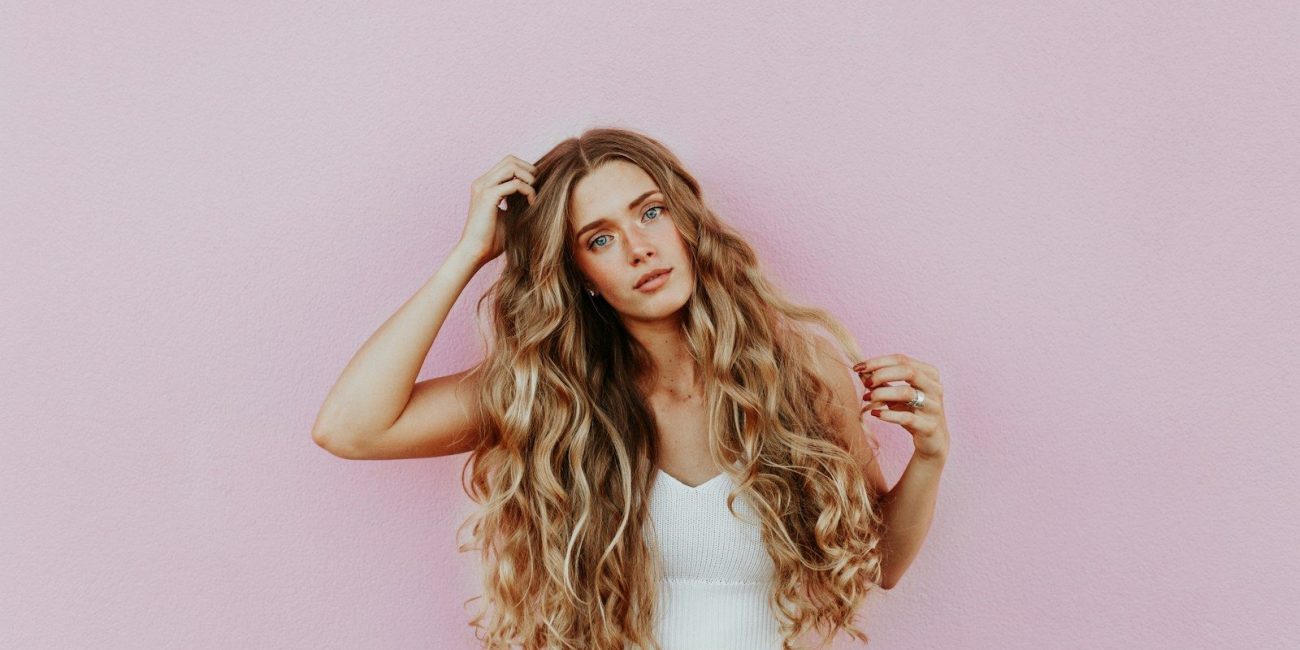 woman standing next to pink wall while scratching her head