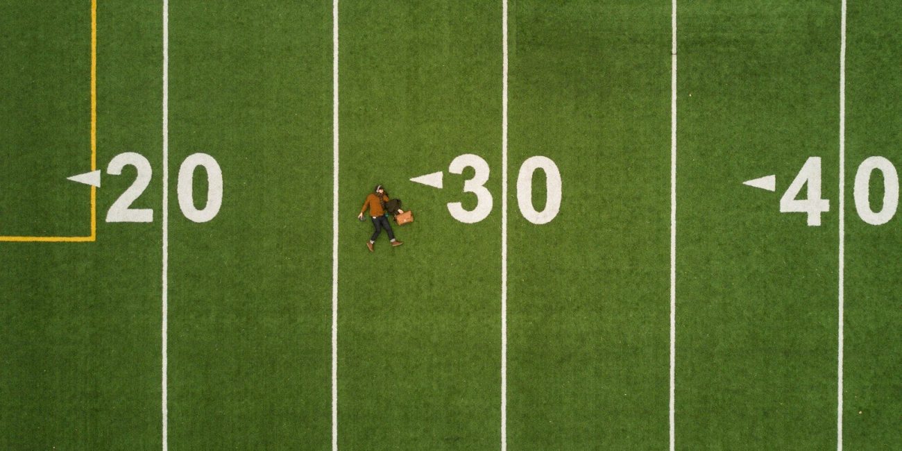 man lying on 30 yards on football field